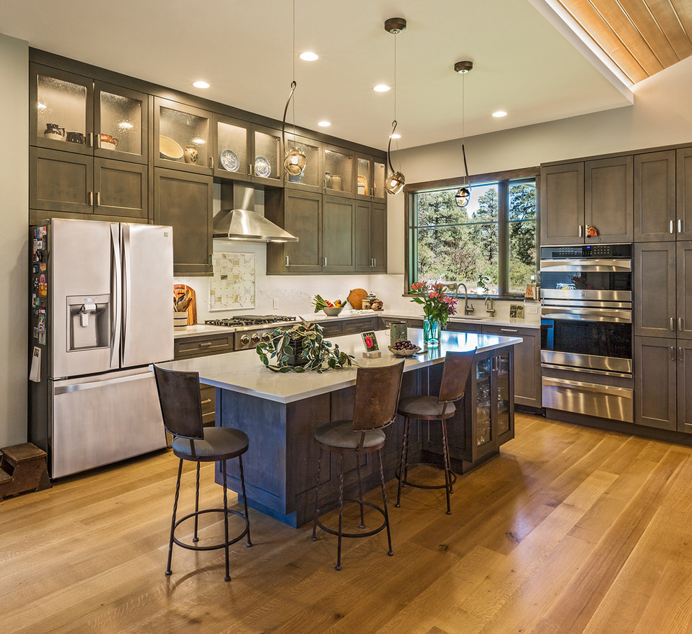 Inspiration for a rustic l-shaped medium tone wood floor and brown floor kitchen remodel with shaker cabinets, dark wood cabinets, stainless steel appliances and an island