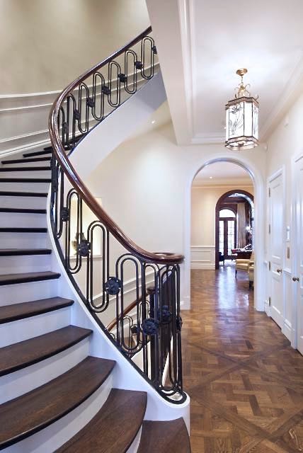 Photo of a large traditional wood curved staircase in Other with painted wood risers and metal railing.