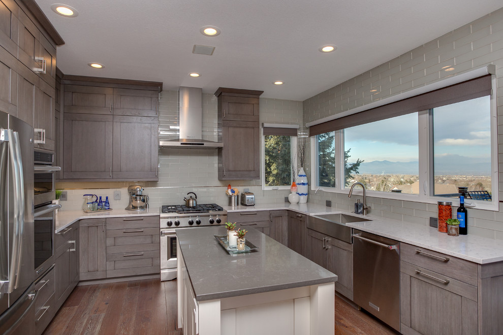 Large transitional u-shaped medium tone wood floor eat-in kitchen photo in Denver with a farmhouse sink, shaker cabinets, gray cabinets, quartz countertops, gray backsplash, glass tile backsplash, stainless steel appliances and an island