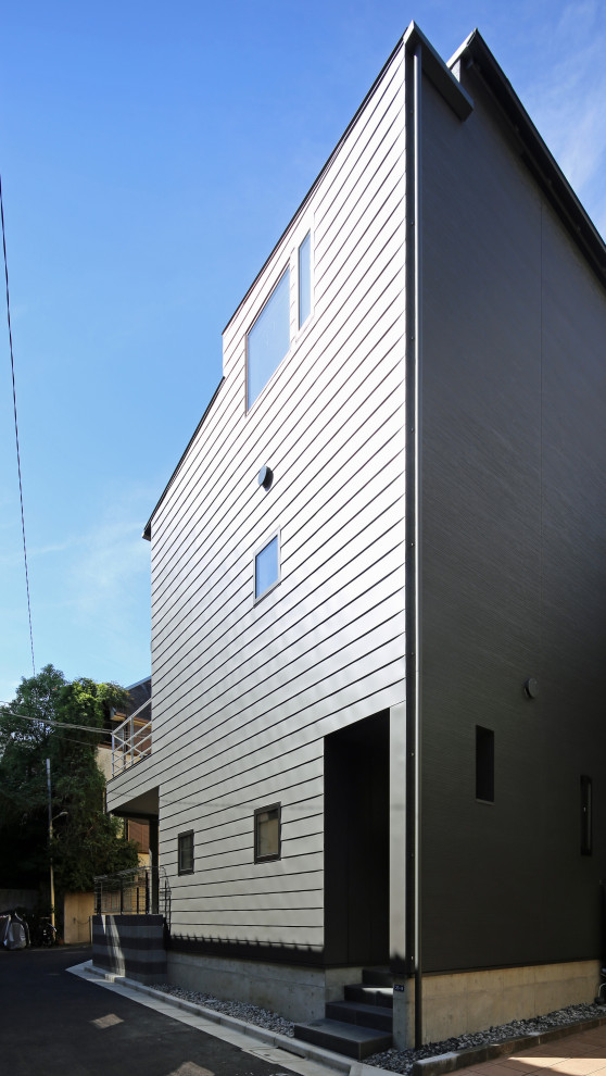 Mittelgroßes, Dreistöckiges Modernes Einfamilienhaus mit schwarzer Fassadenfarbe, Pultdach und Blechdach in Tokio