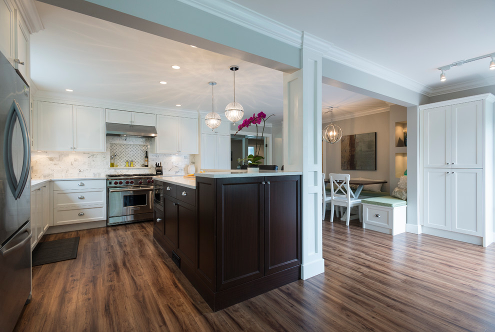 Inspiration for a mid-sized transitional l-shaped medium tone wood floor open concept kitchen remodel in Vancouver with an undermount sink, shaker cabinets, white cabinets, quartz countertops, white backsplash, stone tile backsplash, stainless steel appliances and an island