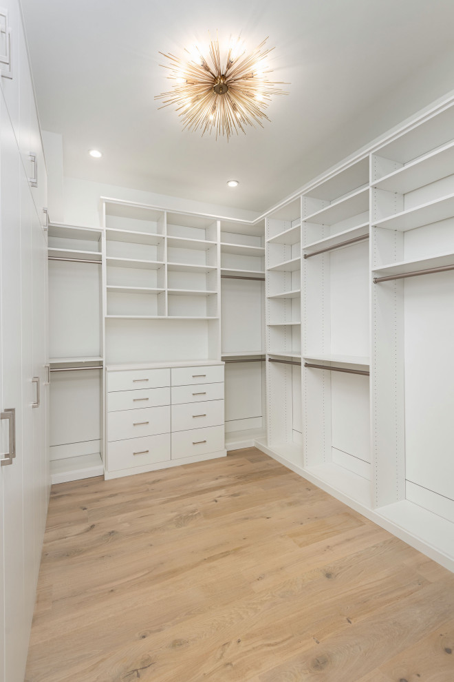 Design ideas for a large modern women's walk-in wardrobe in Charleston with flat-panel cabinets, white cabinets, light hardwood floors and beige floor.