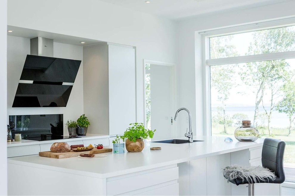 Mid-sized scandinavian galley separate kitchen in Aarhus with a single-bowl sink, flat-panel cabinets, white cabinets, with island, laminate benchtops, black splashback and glass tile splashback.