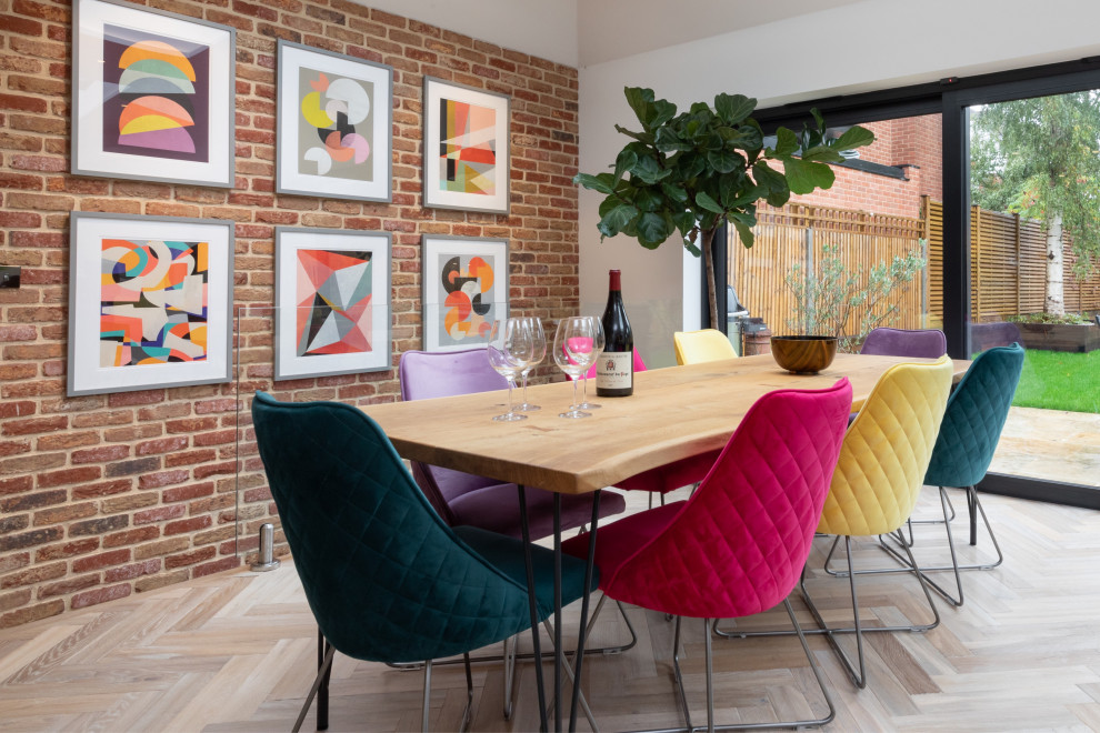 Idée de décoration pour une grande salle à manger ouverte sur la cuisine design avec un mur multicolore, un sol en bois brun, un manteau de cheminée en brique, un sol marron et un mur en parement de brique.