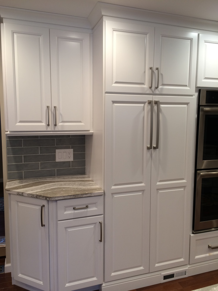 Inspiration for a mid-sized transitional u-shaped medium tone wood floor and brown floor eat-in kitchen remodel with an undermount sink, raised-panel cabinets, white cabinets, granite countertops, blue backsplash, ceramic backsplash, stainless steel appliances, a peninsula and gray countertops
