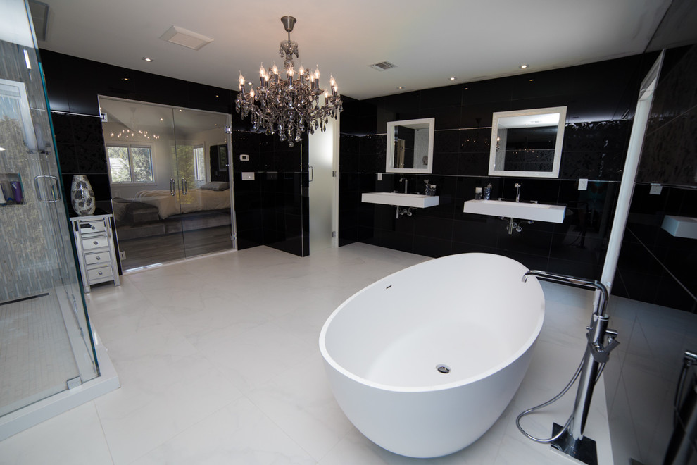 Large contemporary master bathroom in New York with an integrated sink, open cabinets, white cabinets, engineered quartz benchtops, a freestanding tub, a corner shower, a one-piece toilet, black tile, glass sheet wall, black walls and concrete floors.