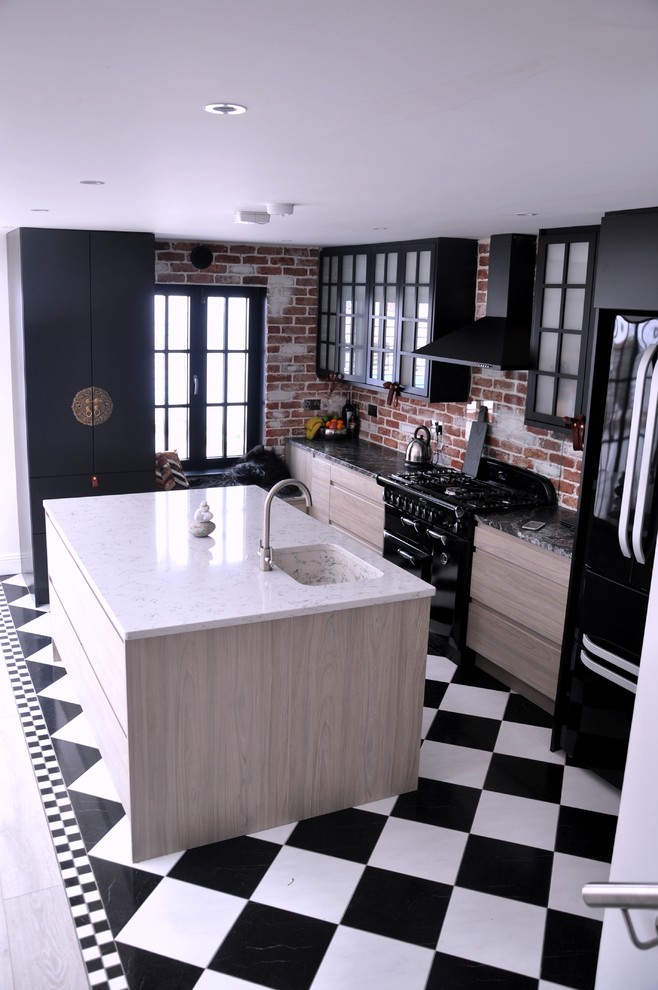 Photo of a mid-sized industrial l-shaped eat-in kitchen in Dublin with an integrated sink, flat-panel cabinets, black cabinets, solid surface benchtops, brick splashback, black appliances, ceramic floors, with island, orange splashback and multi-coloured floor.