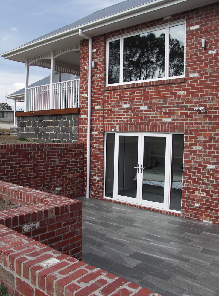 Photo of a large traditional two-storey brick red exterior in Melbourne with a gable roof.