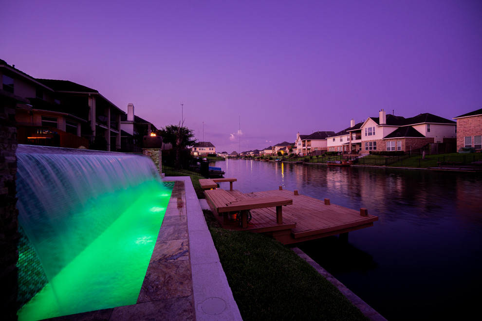 Photo of a large contemporary backyard rectangular infinity pool in Houston with decking.