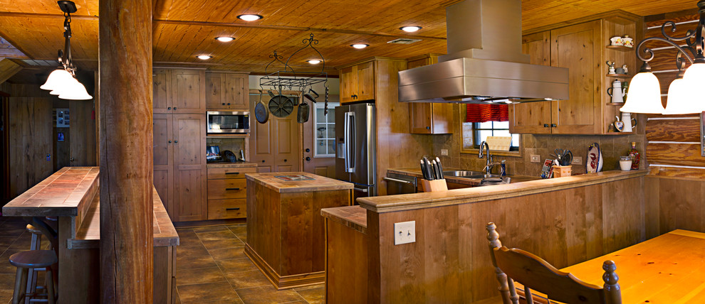 This is an example of a country u-shaped eat-in kitchen in New Orleans with shaker cabinets, medium wood cabinets and stainless steel appliances.