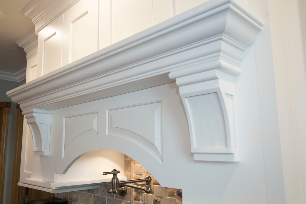 Large transitional l-shaped medium tone wood floor eat-in kitchen photo with an undermount sink, shaker cabinets, white cabinets, granite countertops, gray backsplash, stone tile backsplash, stainless steel appliances and an island