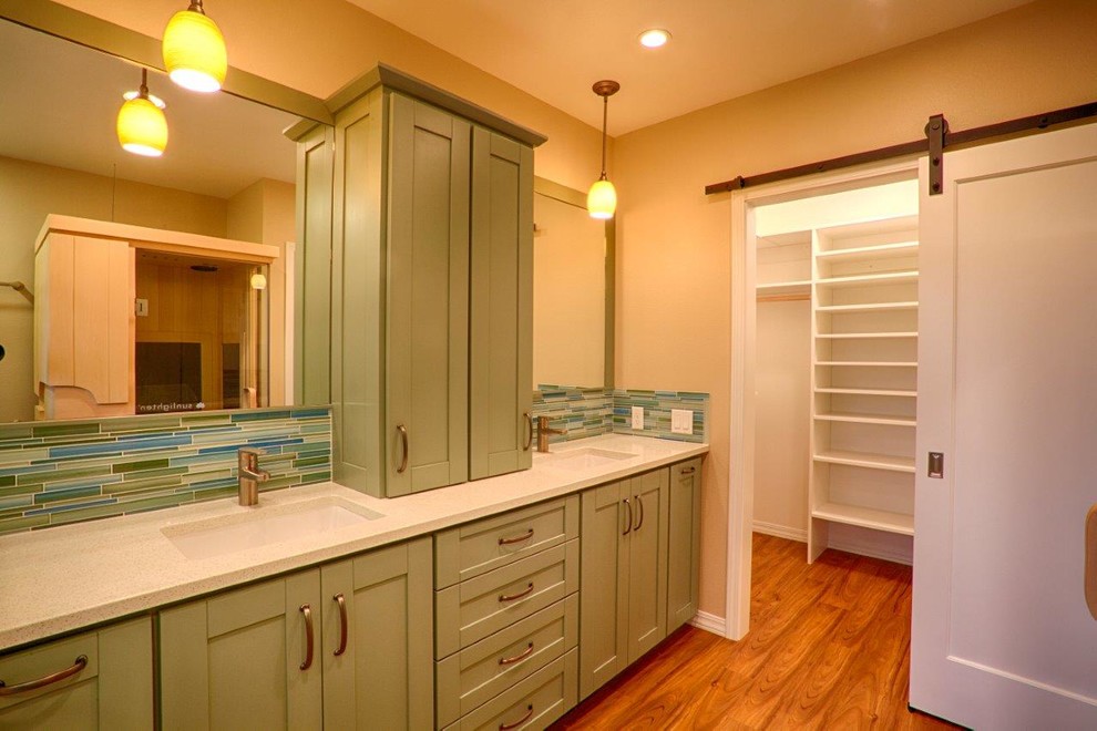 This is an example of a mid-sized contemporary master bathroom in Other with shaker cabinets, green cabinets, a corner shower, a two-piece toilet, multi-coloured tile, glass sheet wall, beige walls, vinyl floors, an undermount sink, engineered quartz benchtops, brown floor, a hinged shower door and white benchtops.