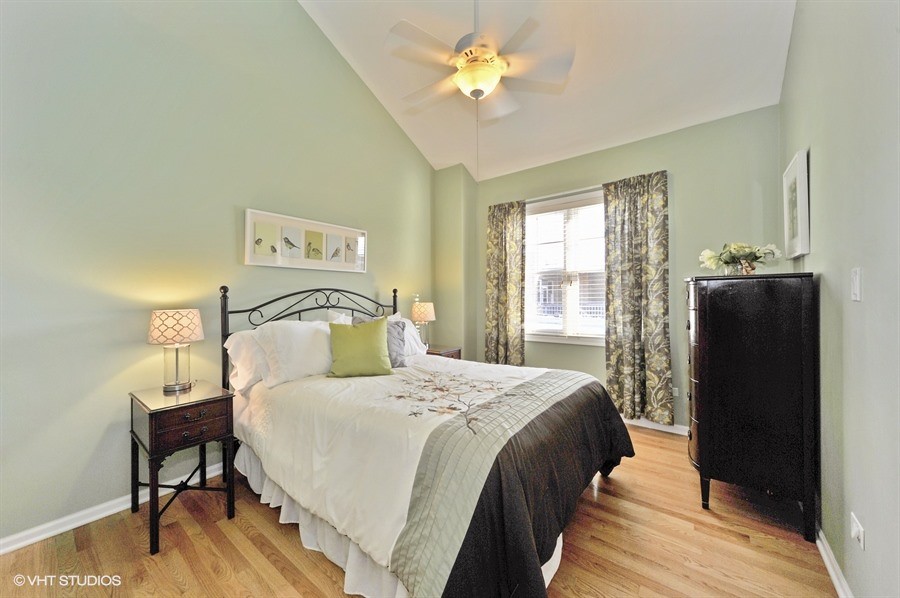 Design ideas for a mid-sized transitional guest bedroom in Chicago with green walls and light hardwood floors.