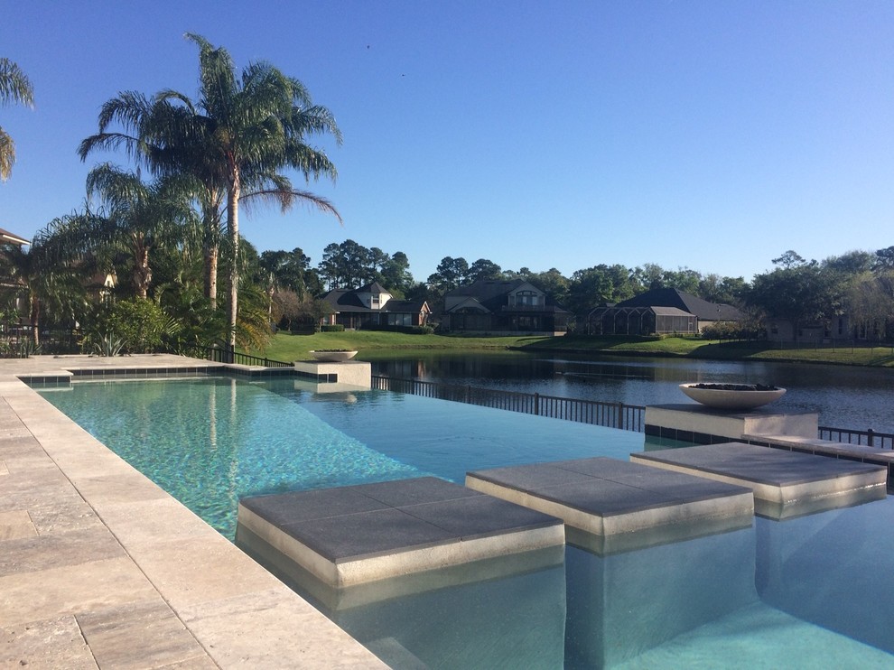 Example of a large transitional backyard tile and rectangular infinity pool design in Jacksonville