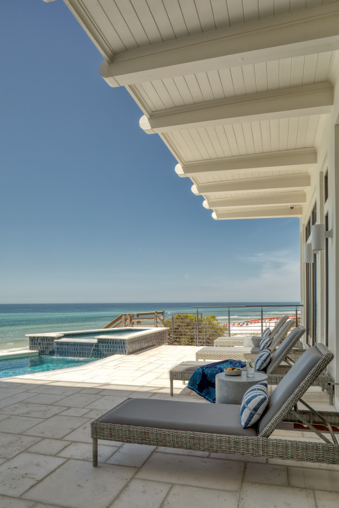 Inspiration for a large beach style backyard rectangular lap pool in Other with a hot tub and natural stone pavers.