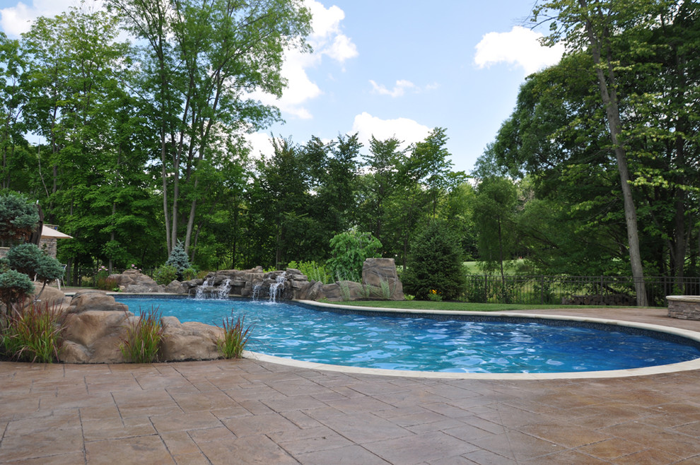 Example of a large mountain style backyard concrete paver and custom-shaped full sun and natural hot tub design in Cleveland