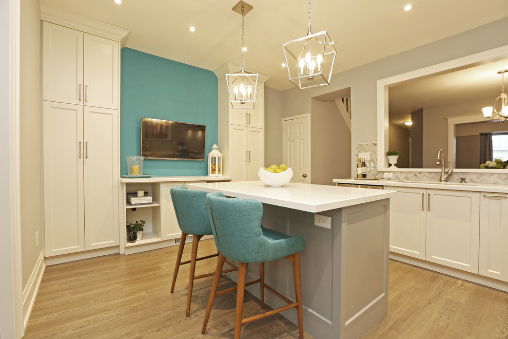 Inspiration for a mid-sized transitional u-shaped light wood floor and brown floor enclosed kitchen remodel in Toronto with an undermount sink, shaker cabinets, white cabinets, solid surface countertops, gray backsplash, stainless steel appliances, an island and white countertops