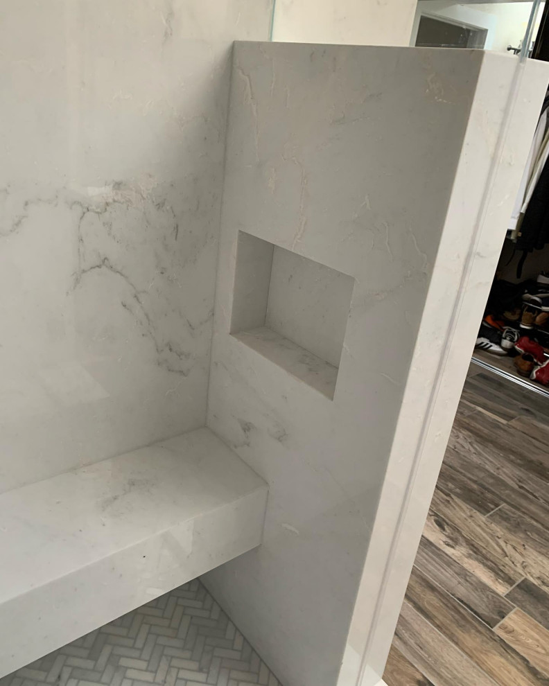 This is an example of a medium sized modern ensuite bathroom in Orange County with all types of shower, white tiles, marble tiles, white walls, light hardwood flooring, marble worktops, a hinged door, white worktops and a shower bench.