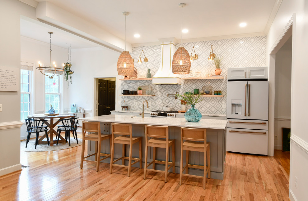 Photo of a small transitional galley eat-in kitchen in DC Metro with a farmhouse sink, recessed-panel cabinets, quartz benchtops, white appliances, with island, grey cabinets, multi-coloured splashback, medium hardwood floors, brown floor and white benchtop.