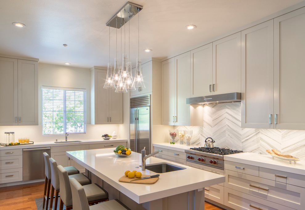 This is an example of a transitional l-shaped kitchen in San Francisco with an undermount sink, shaker cabinets, white cabinets, stainless steel appliances, medium hardwood floors and with island.