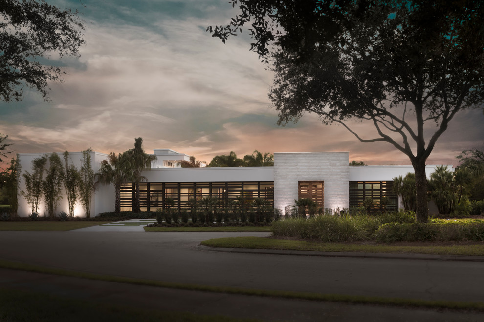 Design ideas for an expansive contemporary one-storey white exterior in Orlando with stone veneer and a flat roof.