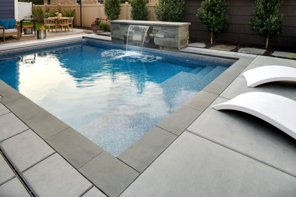 Foto di una piscina design rettangolare di medie dimensioni e dietro casa con pavimentazioni in cemento