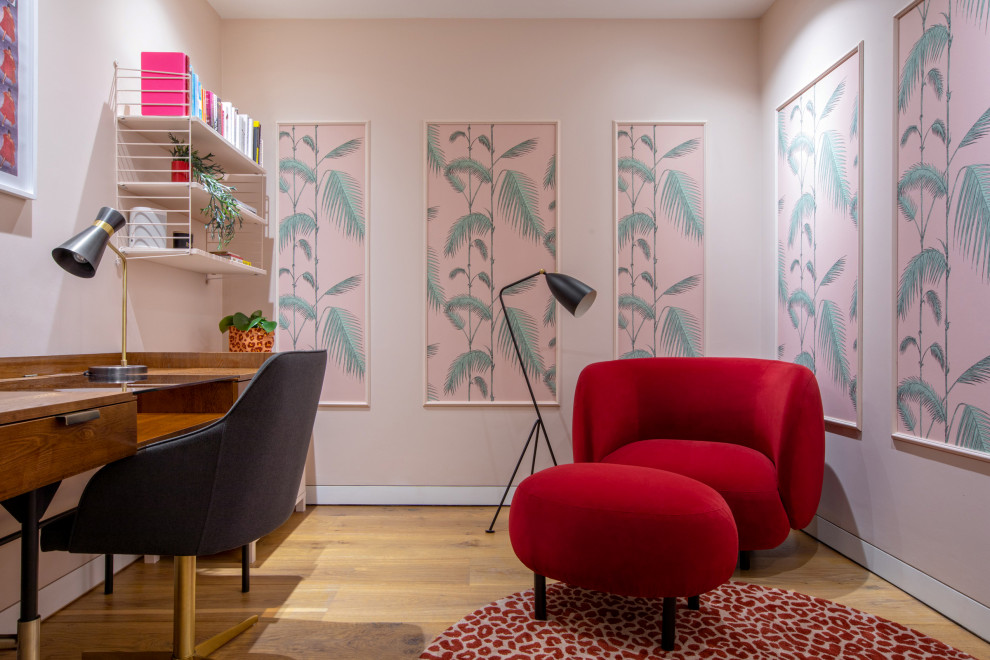 This is an example of a medium sized contemporary study in London with pink walls, light hardwood flooring, a freestanding desk and wallpapered walls.