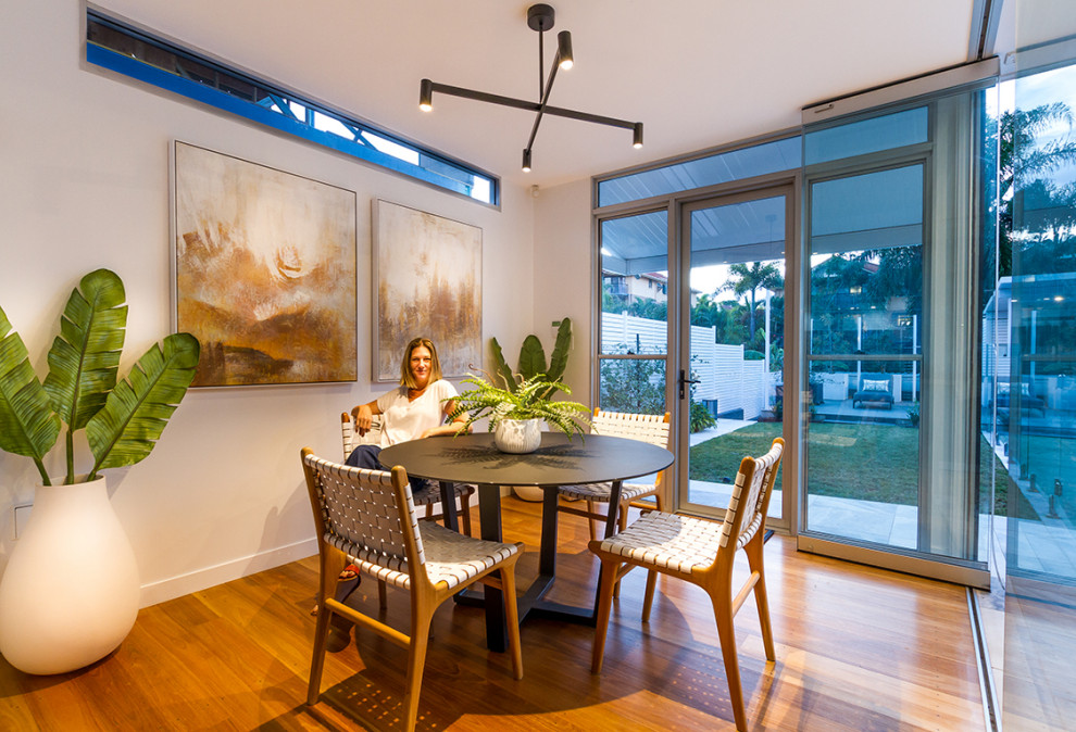 Design ideas for a mid-sized contemporary open plan dining in Brisbane with white walls, medium hardwood floors and brown floor.