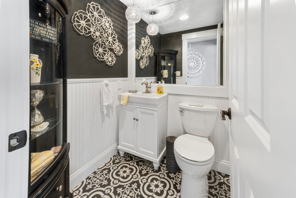 Inspiration for a small country powder room in Cincinnati with white cabinets, a two-piece toilet, grey walls, cement tiles, black floor and white benchtops.