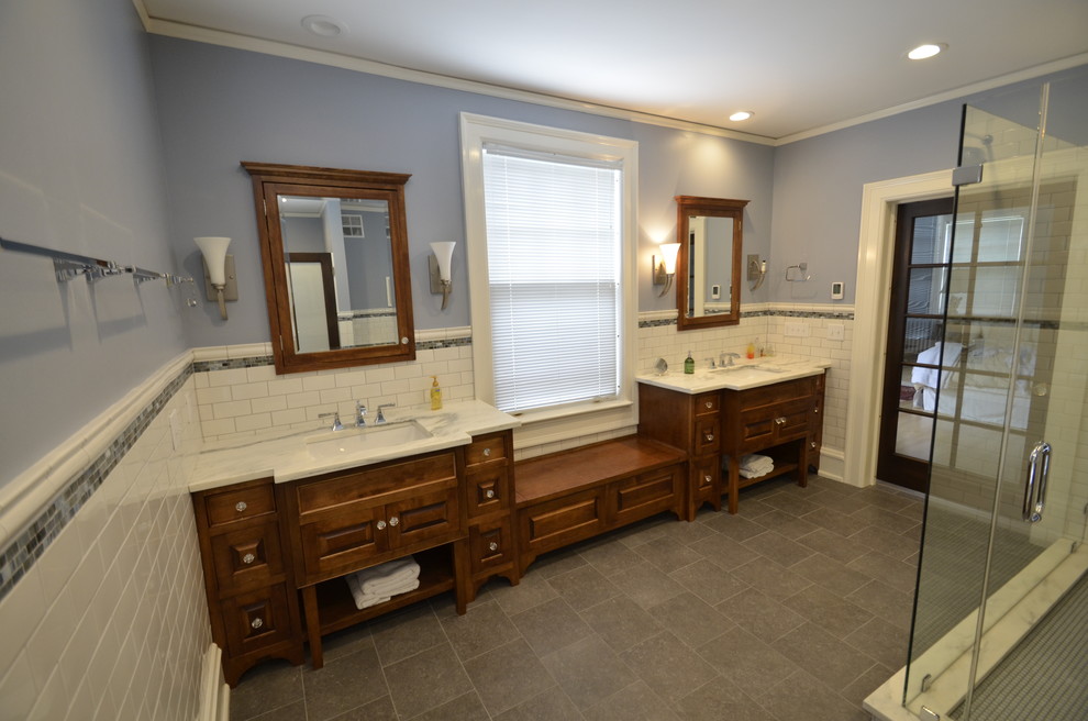 This is an example of a traditional master bathroom in Milwaukee with furniture-like cabinets, marble benchtops, a corner shower, gray tile, blue walls, medium wood cabinets, slate floors and an undermount sink.