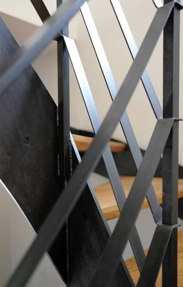 Aménagement d'un escalier courbe industriel avec des marches en bois et un garde-corps en métal.