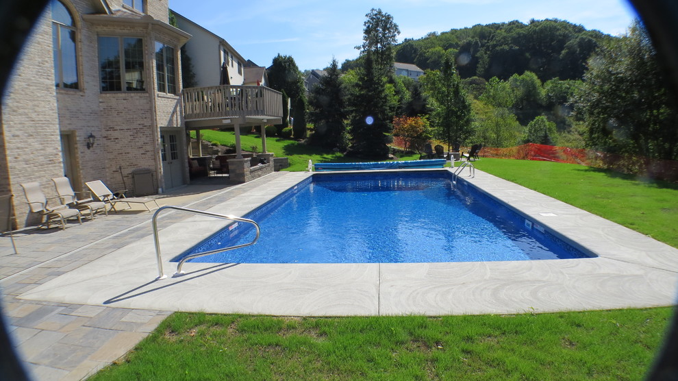 Example of a large minimalist backyard stamped concrete and rectangular pool design