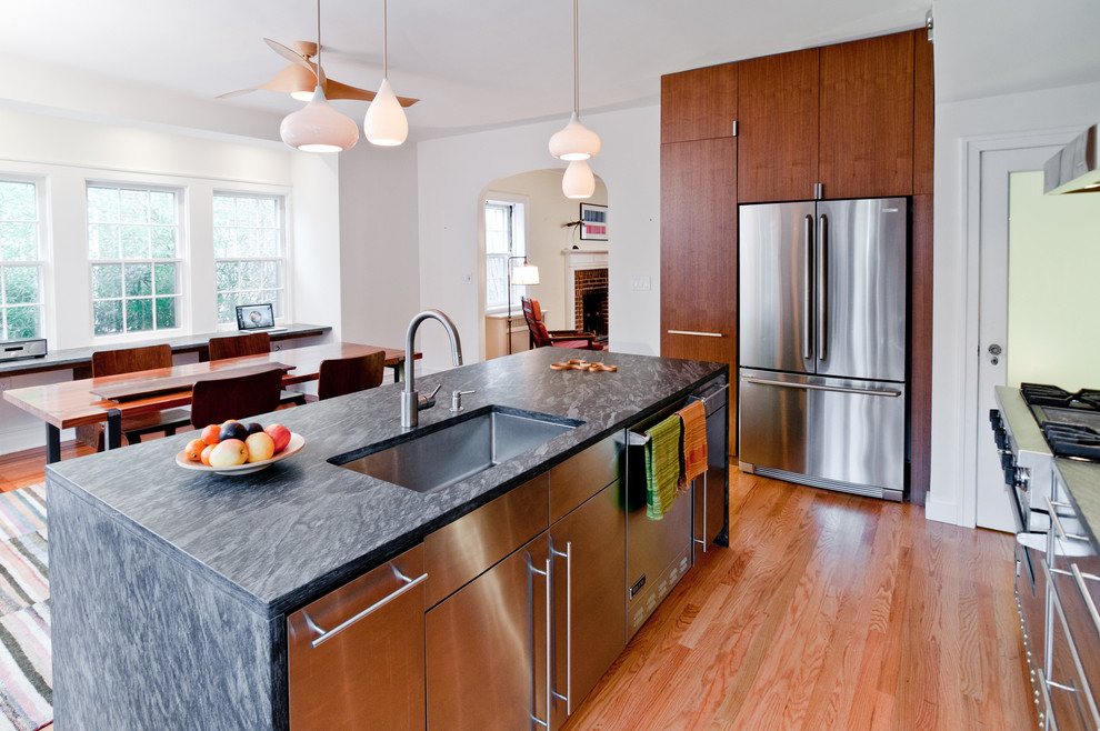 Modern eat-in kitchen in New York with stainless steel appliances, stainless steel cabinets, a single-bowl sink and flat-panel cabinets.