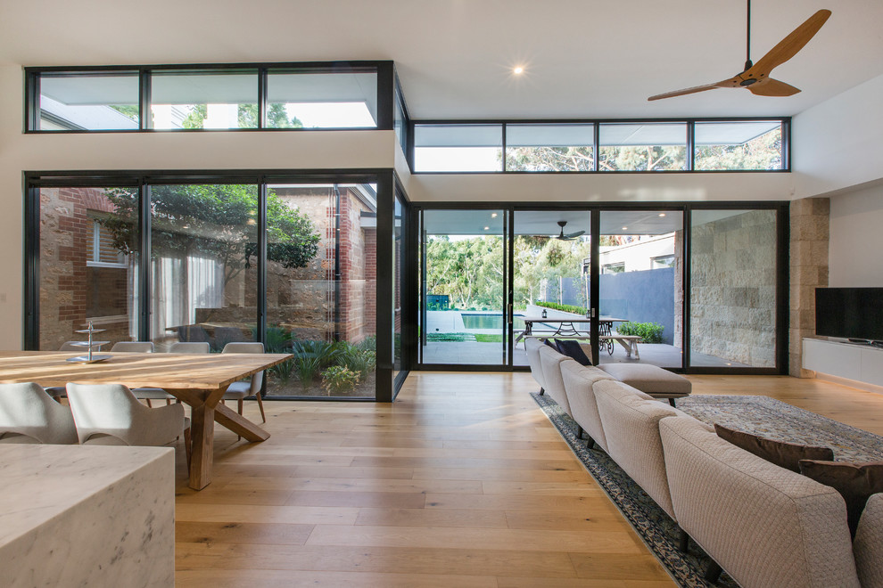 Large contemporary open concept living room in Adelaide with white walls, medium hardwood floors, a standard fireplace, a stone fireplace surround and a freestanding tv.