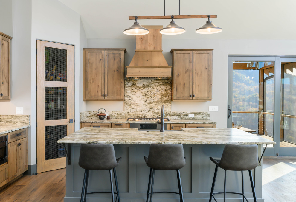 Transitional l-shaped medium tone wood floor and brown floor eat-in kitchen photo with an undermount sink, shaker cabinets, medium tone wood cabinets, multicolored backsplash, stone slab backsplash, stainless steel appliances, an island and multicolored countertops