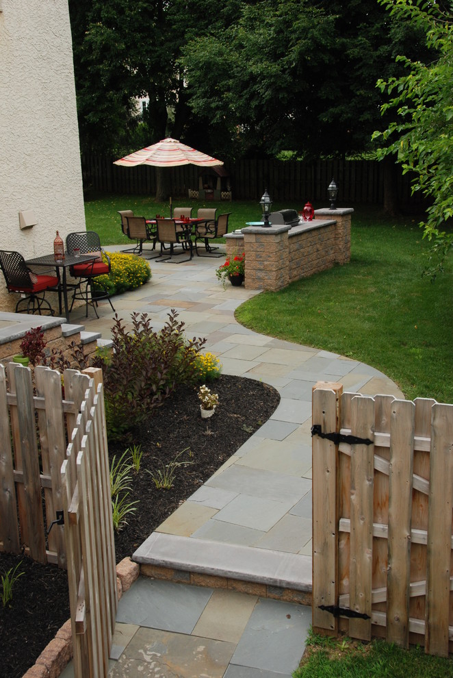 Photo of a small traditional side yard patio in Philadelphia with natural stone pavers, an outdoor kitchen and no cover.
