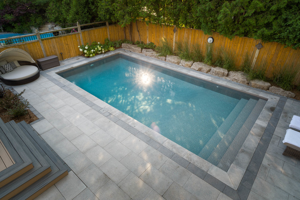 Inspiration for a mid-sized transitional backyard rectangular pool in Toronto with concrete pavers.