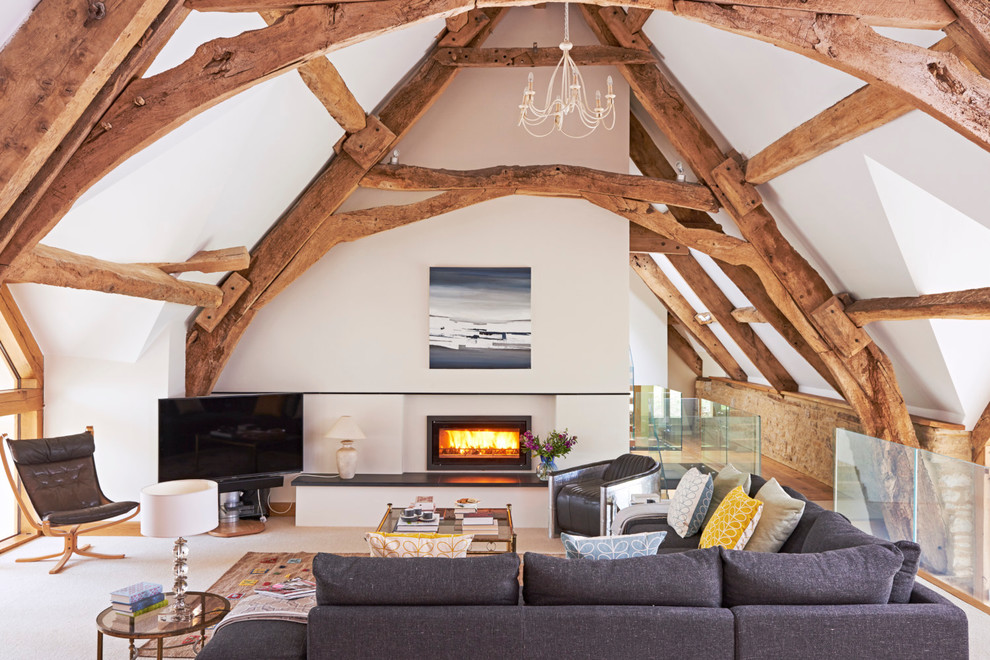 Inspiration for a country loft-style family room in Gloucestershire with white walls, carpet, a ribbon fireplace and a freestanding tv.
