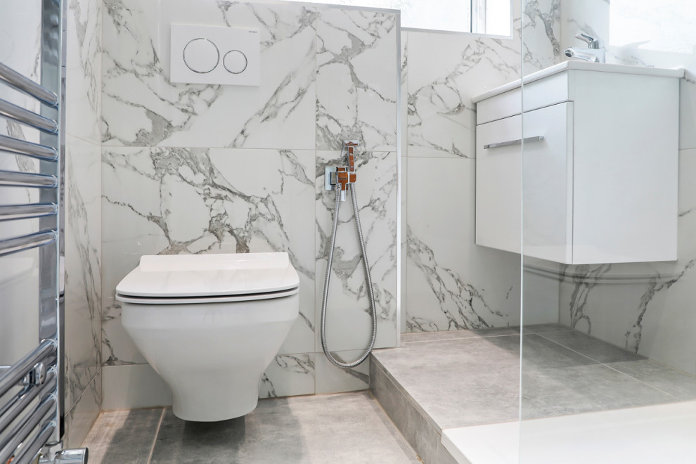 Small contemporary kids bathroom in London with flat-panel cabinets, white cabinets, an open shower, a wall-mount toilet, white tile, ceramic tile, white walls, cement tiles, a wall-mount sink, grey floor and an open shower.