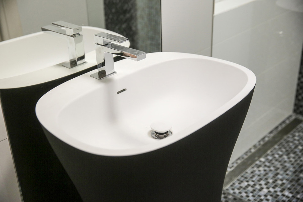 Photo of a mid-sized contemporary bathroom in Melbourne with recessed-panel cabinets, a curbless shower, a one-piece toilet, black and white tile, mosaic tile, white walls, mosaic tile floors, a pedestal sink and solid surface benchtops.