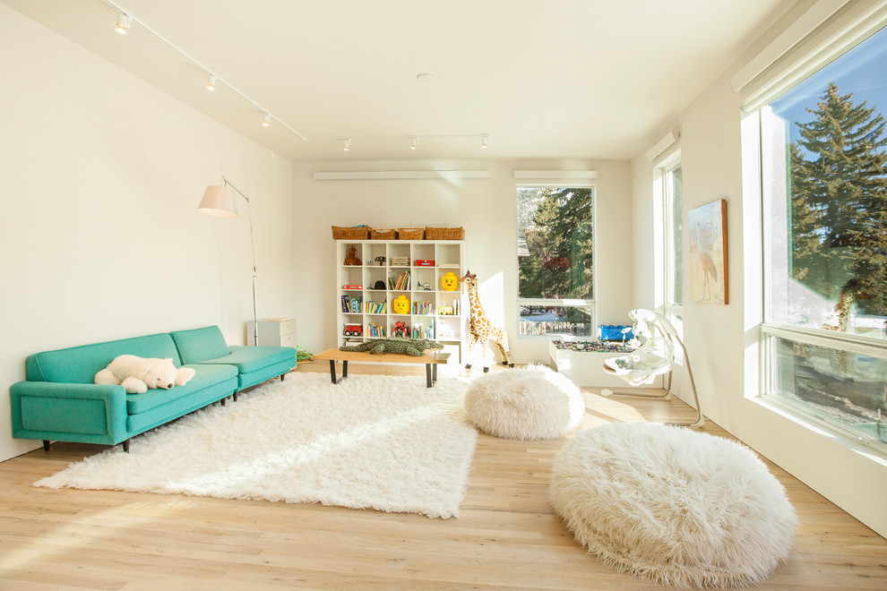 Contemporary gender-neutral kids' playroom in Other with white walls and light hardwood floors.