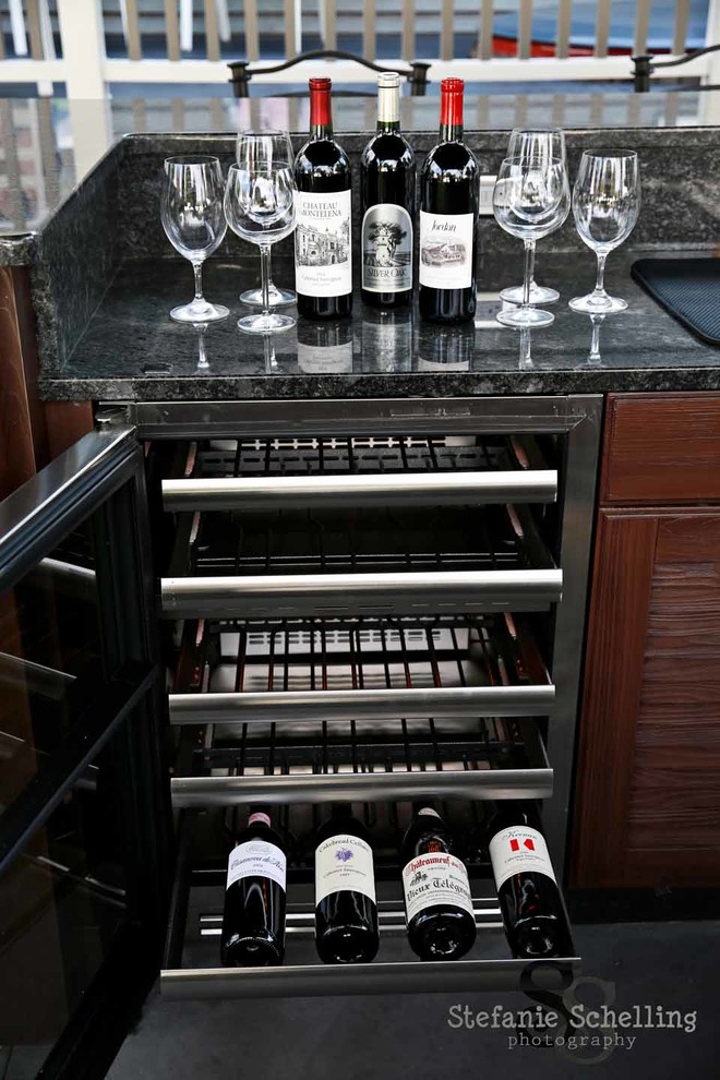 This is an example of a large modern u-shaped wet bar in Other with a built-in sink, medium wood cabinets, granite worktops and concrete flooring.