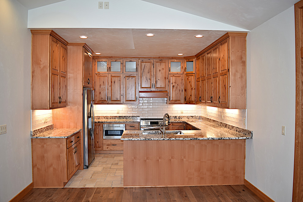 Open concept kitchen - mid-sized galley open concept kitchen idea with an undermount sink, raised-panel cabinets, granite countertops, white backsplash, ceramic backsplash, stainless steel appliances and a peninsula