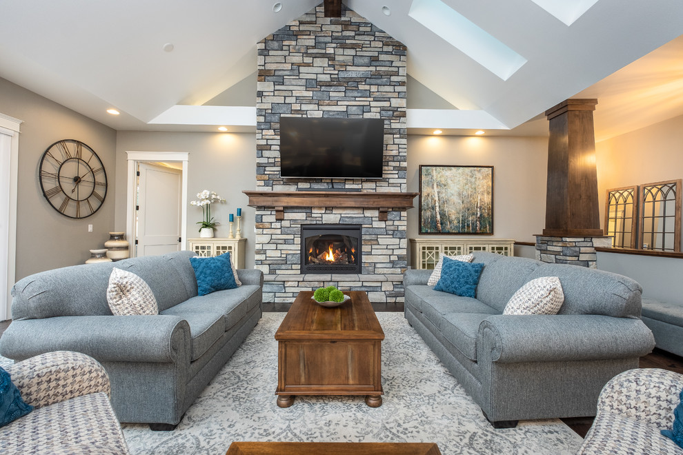 Inspiration for a traditional family room in Other with grey walls, a stone fireplace surround, a wall-mounted tv and a wood stove.