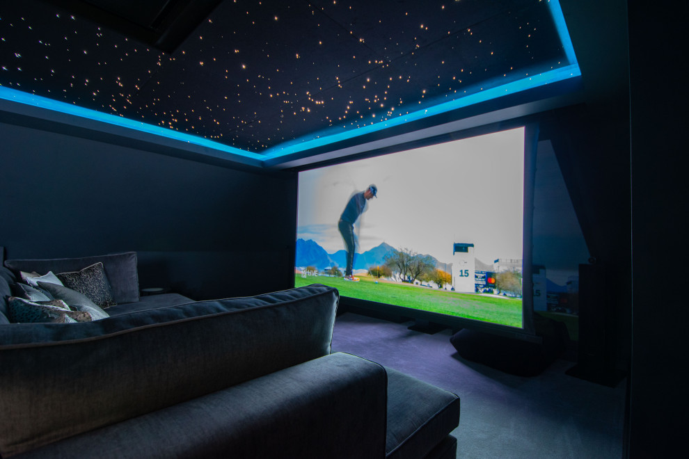 Inspiration for a large contemporary enclosed home theatre in Surrey with black walls, carpet, a projector screen and black floor.