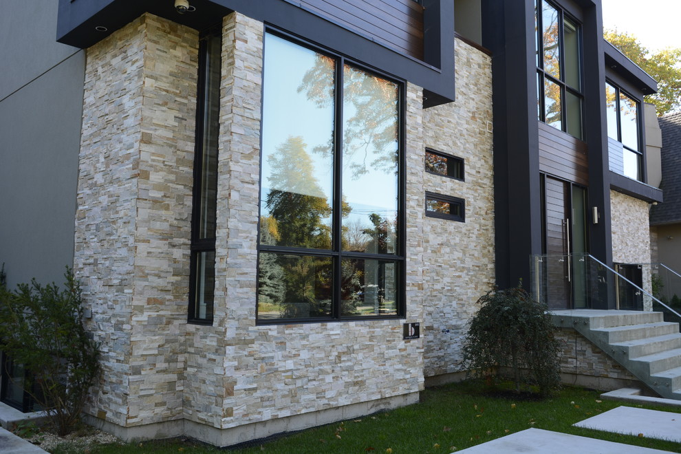Large contemporary two-storey grey exterior in Toronto with stone veneer.