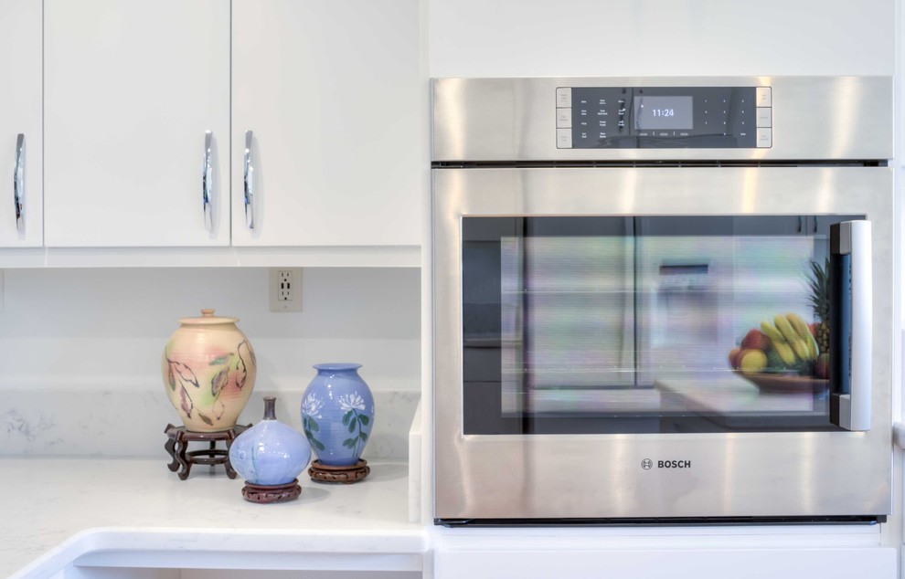 Large transitional u-shaped medium tone wood floor and brown floor enclosed kitchen photo in Hawaii with an undermount sink, flat-panel cabinets, white cabinets, quartz countertops, white appliances and an island