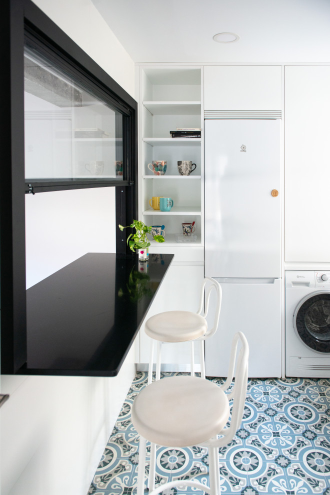 Photo of a modern l-shaped eat-in kitchen in Madrid with a drop-in sink, flat-panel cabinets, quartz benchtops, white appliances, ceramic floors, no island, blue floor and white benchtop.