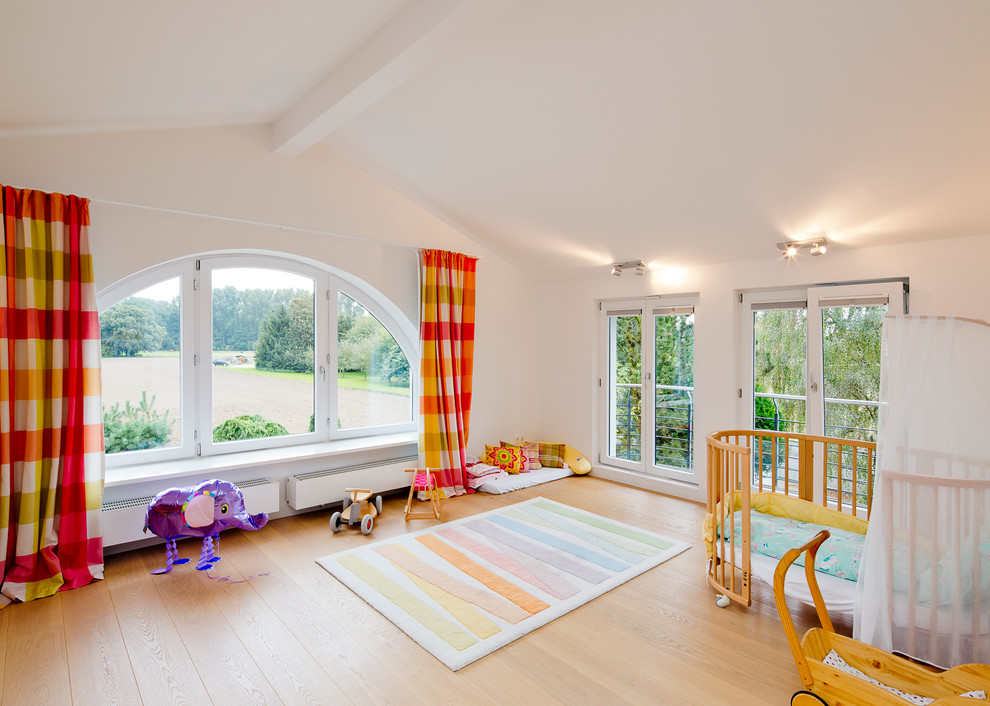 Inspiration for a large contemporary gender-neutral kids' playroom for kids 4-10 years old in Dusseldorf with light hardwood floors and beige walls.