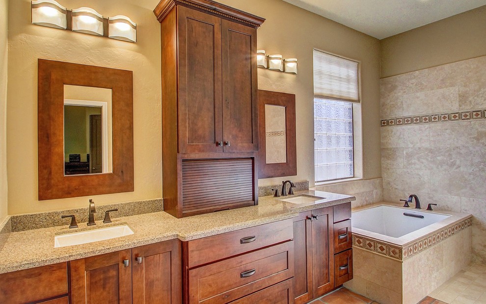 Photo of a large transitional master bathroom in Phoenix with shaker cabinets, medium wood cabinets, an undermount tub, stone tile, engineered quartz benchtops, a two-piece toilet, beige tile, beige walls and travertine floors.